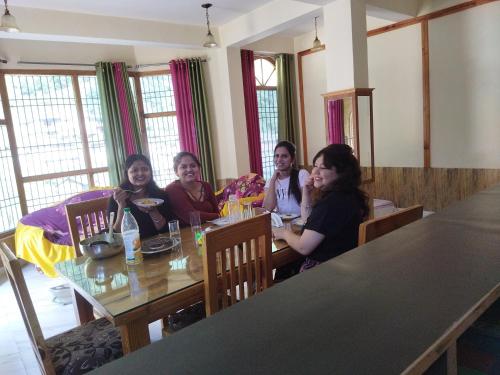 a group of people sitting at a table at Orange sky home stay gadaGushaini near jibhi in Jibhi