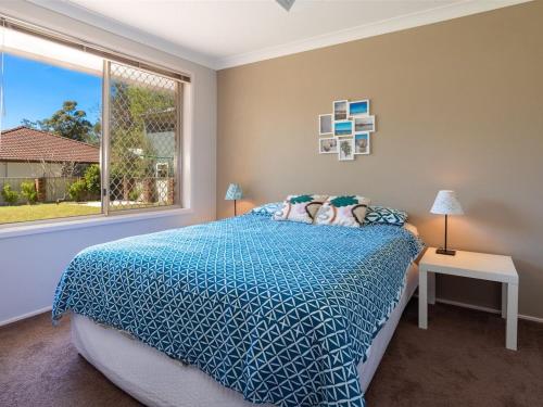 1 dormitorio con 1 cama con edredón azul y ventana en Corner Haven, en Myola