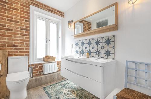 a bathroom with a toilet and a sink and a mirror at Seagrass Cottage in Southwold, Stunning Property with Views! in Southwold