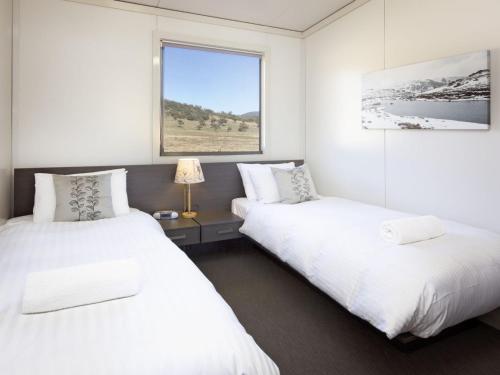2 łóżka w białym pokoju z oknem w obiekcie Ecocrackenback 19 Sustainable chalet close to the slopes w mieście Crackenback