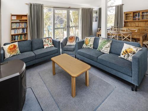 a living room with two blue couches and a table at Matilda - 3BR Home l Central Location l Amazing Lake Views l WiFi l BBQ in Jindabyne