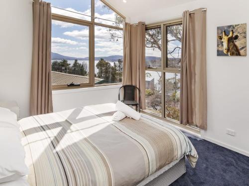 a bedroom with a bed and large windows at Matilda Spacious centrally located with great lake views in Jindabyne
