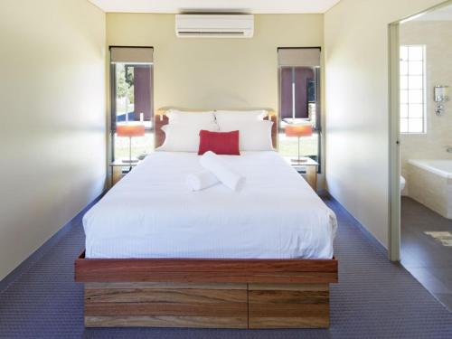 a bedroom with a large white bed and a tub at Kickenback Studio Contemporary accommodation in the heart of Crackenback in Crackenback
