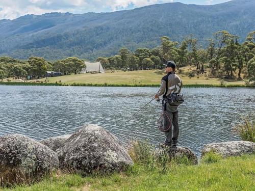 a man standing on rocks near a body of water at Kickenback Studio - Gym l Indoor Pool l Tennis l Air-Con l WiFi l BBQ in Crackenback