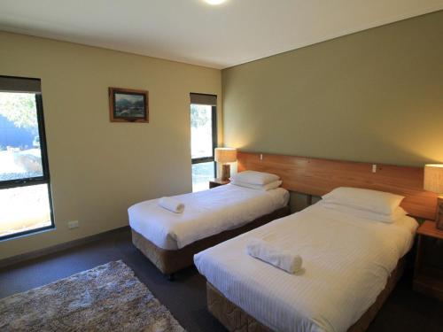 a hotel room with two beds and two windows at Kickenback Chalet - 2BR Chalet l Gym l Indoor Pool l Tennis Court l WiFi l Air-Con in Crackenback