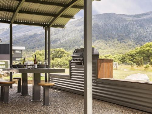 a patio with a table and a grill with a view at Kickenback Chalet - 2BR Chalet l Gym l Indoor Pool l Tennis Court l WiFi l Air-Con in Crackenback
