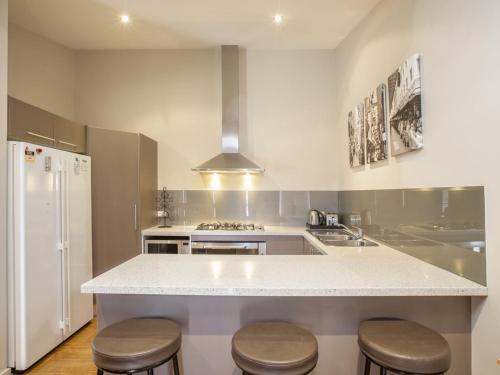 a kitchen with a white counter and stools in it at Khione 1 - 3BR Modern Townhouse l Mountain Views l WiFi l BBQ l Smart TV in Jindabyne