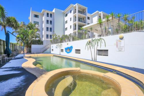 a swimming pool in front of a building at The Point Resort in Bargara