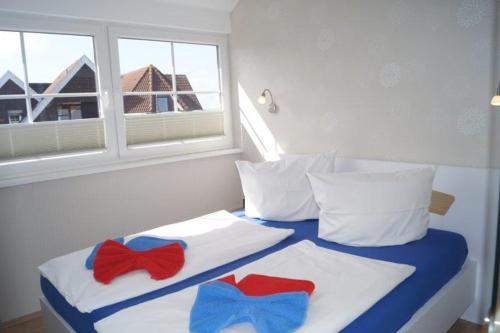 a bed with two red and blue bow ties on it at Komfortappartement Robbe in Neuharlingersiel