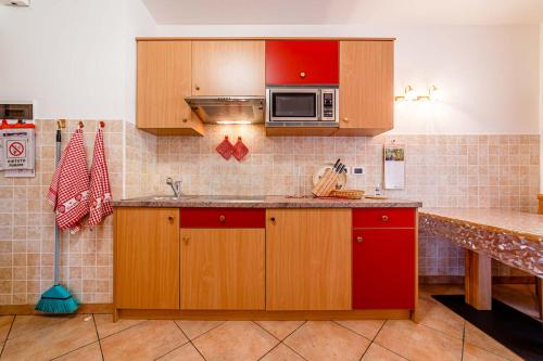 a kitchen with red cabinets and a microwave at Appartamenti Ciesa Padon in Rocca Pietore