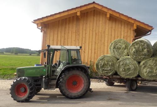 a green tractor pulling a trailer full of hay at Beim Heiß'n in Staudach-Egerndach