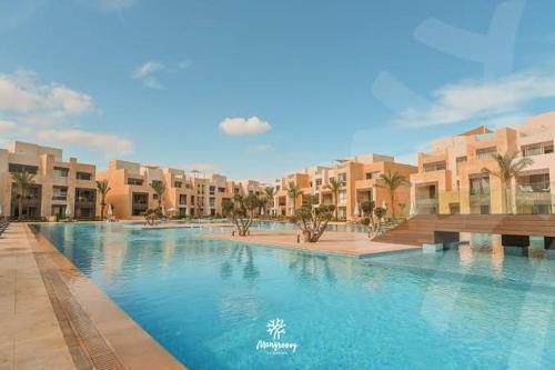 a large swimming pool in a resort with buildings at Mangroovy - Elgouna Authentic Designer shared home 2 BDR each with private bathroom for Kitesurfers with Pool View & Beach Access in Hurghada