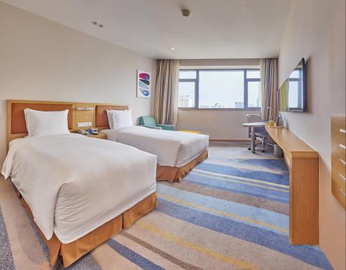 a hotel room with two beds and a desk at Holiday Inn Express Shanghai Zhenping by IHG in Shanghai