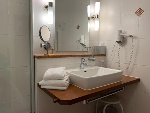 ein Bad mit einem Waschbecken und einem Spiegel in der Unterkunft Pension Kramerhof in Taufkirchen