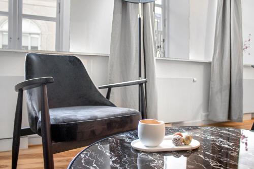 a black chair and a table with a cup of coffee at Sanders Regent - Smart Two-Bedroom Apartment Near Central Square in Copenhagen