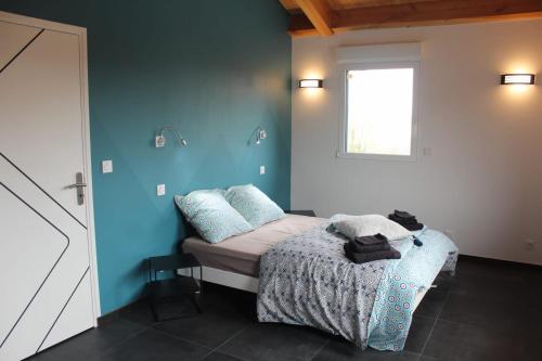 een slaapkamer met een bed met blauwe muren en een raam bij L'AYMERAUDE in Messinhac