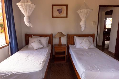 two twin beds in a room with a lamp at Morrumbene Beach Resort in Morrumbene