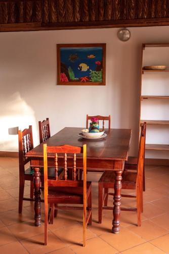 a wooden dining room table with chairs and a painting at Morrumbene Beach Resort in Morrumbene