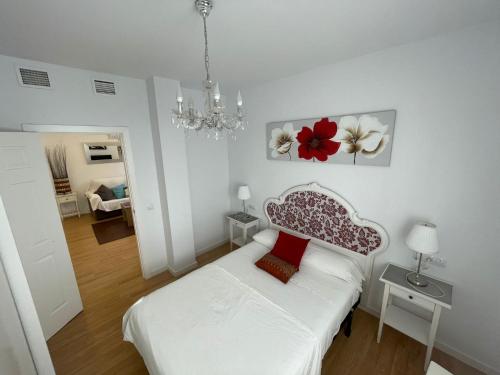 タリファにあるApartamento Vacacional Manoliの白いベッドルーム(ベッド1台、シャンデリア付)