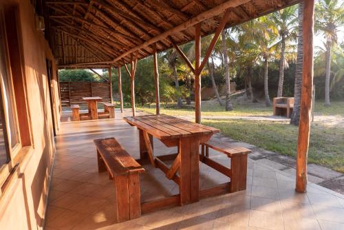 a wooden picnic table and benches on a porch at Morrumbene Beach Resort in Morrumbene