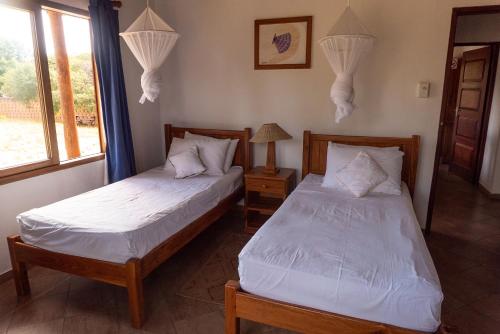 a bedroom with two beds and a window at Morrumbene Beach Resort in Morrumbene