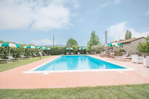 a pool with chairs and umbrellas in a yard at Casa Vacanze Vecchio Granaio in Magione