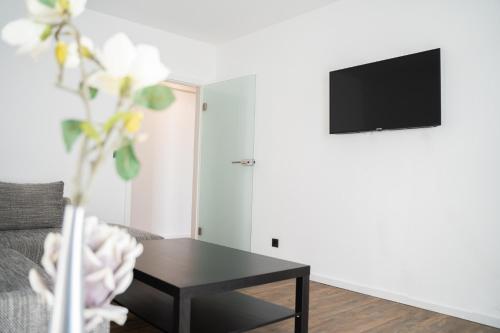 a living room with a table and a tv on a wall at AP Hotel Mannheim Viernheim in Viernheim