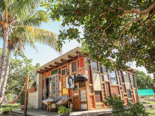 ein Haus am Strand mit einer Palme in der Unterkunft Mozambeat Motel in Praia do Tofo