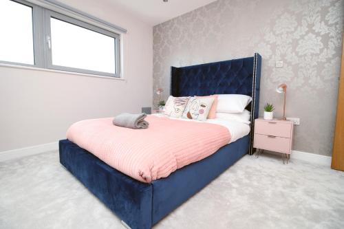 a bedroom with a blue bed and a window at The View - LONG STAY OFFER - Modern Central Apartment and Parking by CTO Serviced Apartments in Cardiff