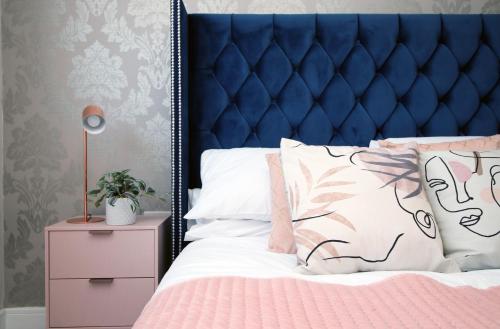 a bedroom with a blue headboard and a pink bed at The View - LONG STAY OFFER - Modern Central Apartment and Parking by CTO Serviced Apartments in Cardiff