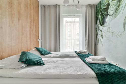 a bedroom with a large bed with green pillows at LTC - Apartments Abrahama Śródmieście in Gdynia