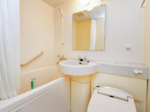 a bathroom with a sink and a toilet and a mirror at APA Hotel Nagoya Marunouchi Ekimae in Nagoya