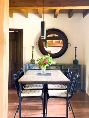 a dining room table with chairs and a vase of flowers at EL CUENTO DE LA ENCINA. Un espacio para sentir in Majaelrayo