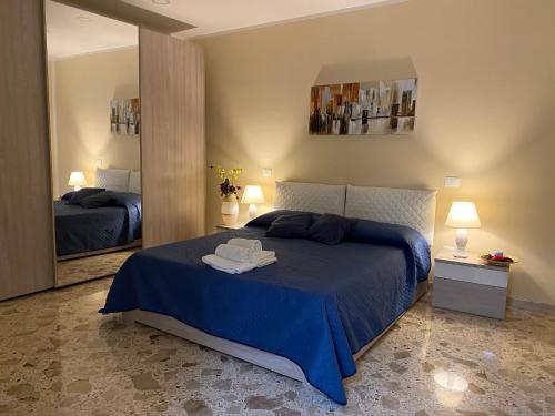 a bedroom with a blue bed and a mirror at Si Viaggiare Apartments in Partinico