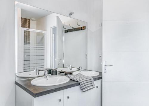 een witte badkamer met 2 wastafels en een spiegel bij L'Exploratrice in Saint-Lunaire