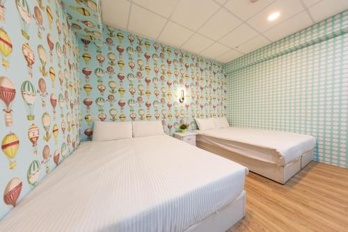a bedroom with two beds and a wall of wallpaper at Liu He Su Hotel in Kaohsiung