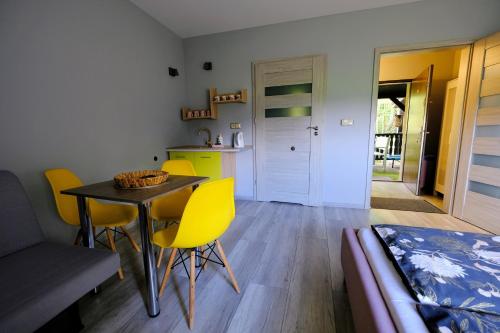 a living room with a table and yellow chairs at Noclegi Wiejski Raj in Chocieszow