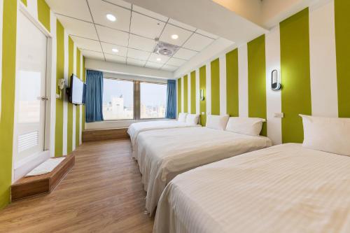 a row of beds in a room with green and white stripes at Liu He Su Hotel in Kaohsiung