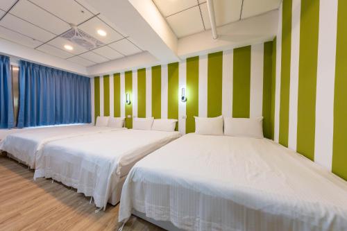 two beds in a room with green and white stripes at Liu He Su Hotel in Kaohsiung