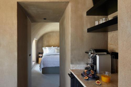 a hotel room with a bed and a kitchen with a counter at Santorini Sky, The Lodge in Pirgos