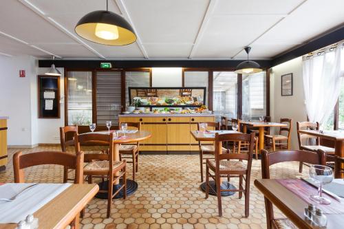 Un restaurante con mesas y sillas y una cocina. en Comfort Hotel Lens - Noyelles Godault, en Noyelles-Godault