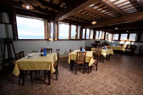 una sala da pranzo con tavoli, sedie e finestre di History Hotel a Valderice