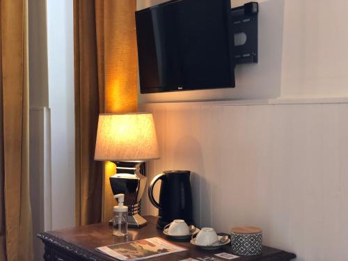 a desk with a lamp and a tv on a wall at Maison d'Hôtes Lassaubatju in Hontanx