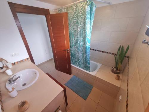 a bathroom with a sink and a shower with a shower curtain at Apartamento El Jameo in Playa Blanca