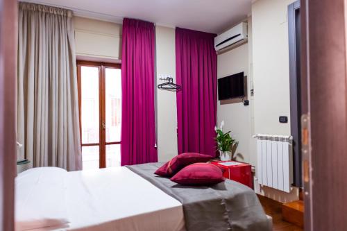 - une chambre avec des rideaux violets et un lit avec des oreillers rouges dans l'établissement Royal Poerio, à Naples