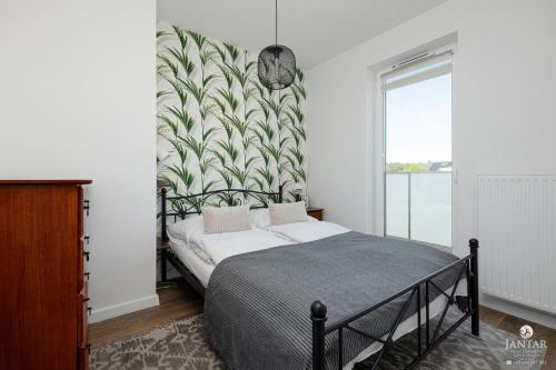 a bedroom with a bed with a green and white wallpaper at JANTAR APARTAMENTY Posesja Kapitańska in Grzybowo