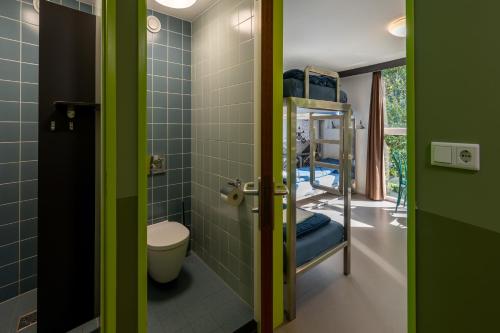 a bathroom with a toilet and a room with bunk beds at Stayokay Hostel Haarlem in Haarlem