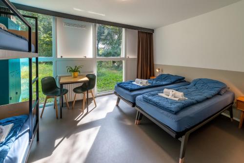 1 Schlafzimmer mit 2 Betten, einem Tisch und Stühlen in der Unterkunft Stayokay Hostel Haarlem in Haarlem