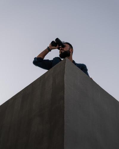 a man standing on top of a wall taking a picture at Santorini Sky, The Lodge in Pirgos