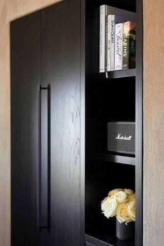 a black cabinet with a refrigerator and books at Santorini Sky, The Lodge in Pirgos